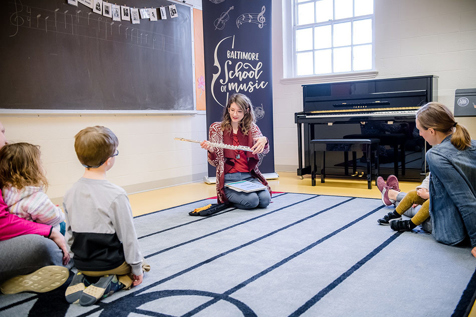 teacher Sarah Greene demonstrating a flute to a Mini Maestro class.