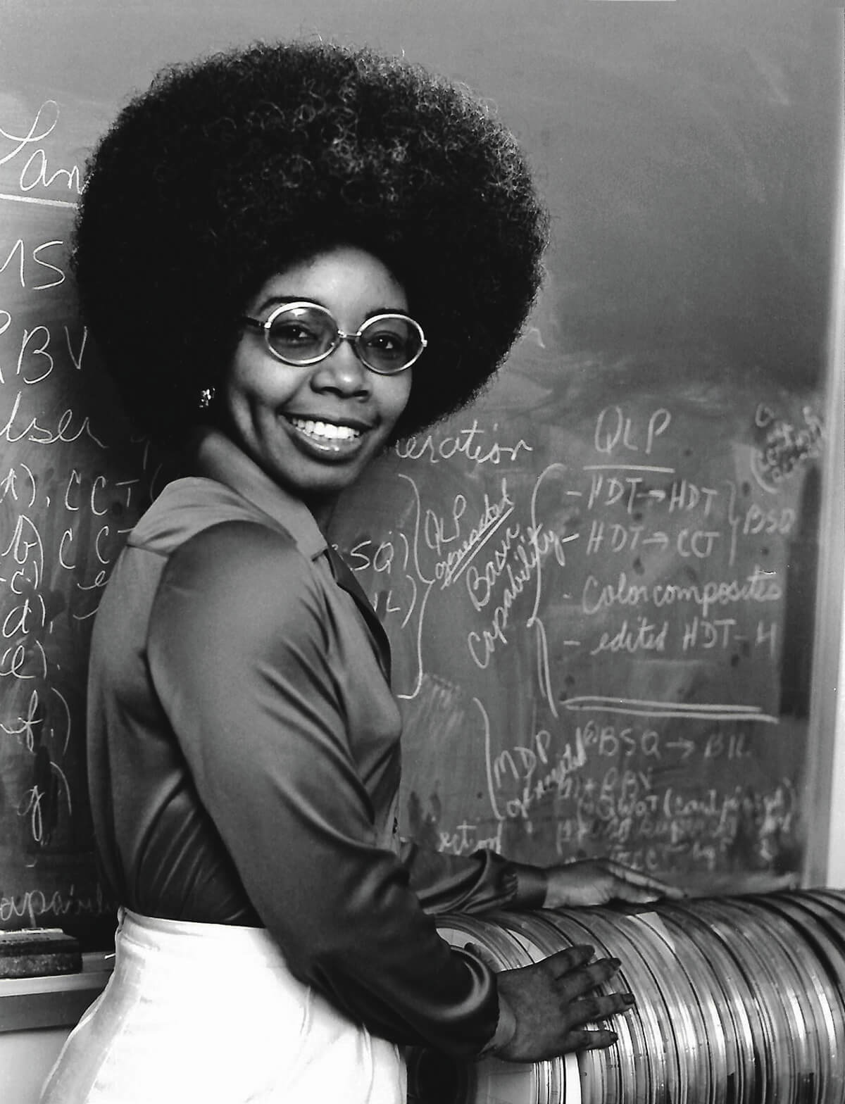 Valerie_L._Thomas_standing_with_a_stack_of_early_Landsat_Computer_Compatible_Tapes_CMYK